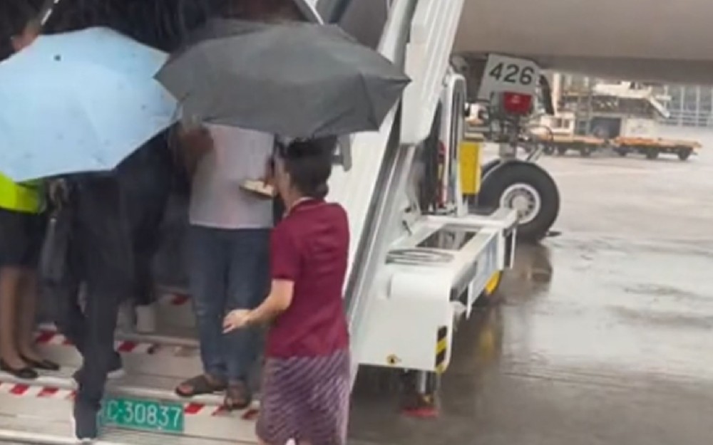 空姐撑伞蹚水送旅客上摆渡车 南航回应